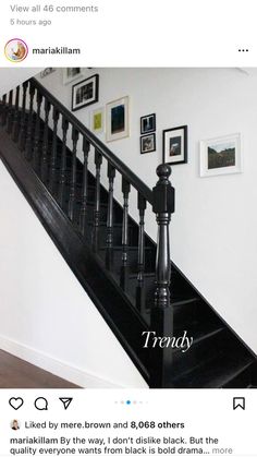 a staircase with black railing and pictures on the wall