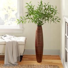 a large plant in a tall vase next to a white bench with a blanket on it