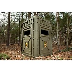 an outhouse in the woods with its door open and two gold emblems on it