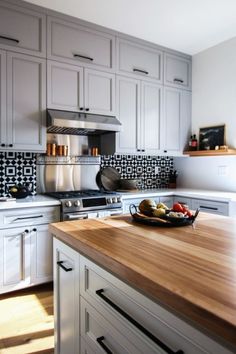 a kitchen with white cabinets and wooden counter tops, including a bowl of fruit on the island