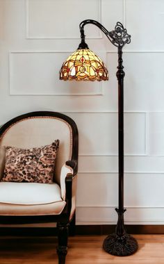 a lamp sitting on top of a wooden floor next to a chair with a pillow