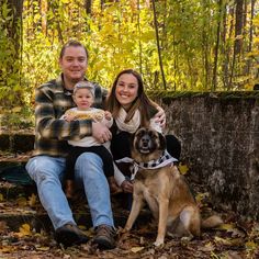 a man, woman and child sitting on a bench with a dog