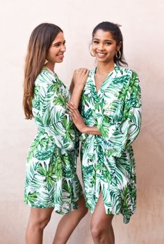 two women standing next to each other wearing green leaves robes