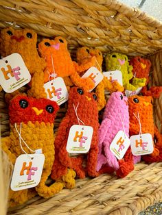 several knitted teddy bears are in a wicker basket with tags attached to them