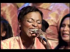 a woman singing into a microphone in front of other women