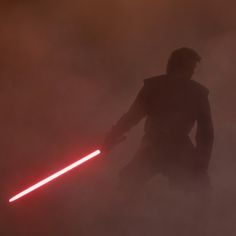 a man with a light saber standing in the fog