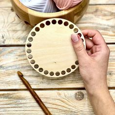 a person is holding a circular object in front of some knitting needles and yarns