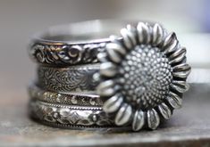 "I love sunflowers! I made this pretty sunshiny set from solid sterling silver. In this set: Four patterned solid sterling silver rings (varying from 2mm-3.8mm in width) featuring a 12mm (1/2\") wonderfully detailed sterling sunflower. Shown in lightly antiqued, but you may choose shiny sterling. Your set will be as pictured. Variations possible upon request. Any size. Gift boxed with a pretty bow." Silver Sunflower Design Ring, Dainty Silver Sunflower Jewelry, Silver Sunflower Design Necklace, Silver Jewelry With Sunflower Design Flower Pendant, Yellow Flower-shaped Jewelry With Sunflower Print, Swiss Blue Topaz Ring, Sunflower Ring, Sterling Silver Stacking Rings, Stacking Ring Set