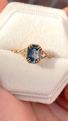 a woman's hand holding an engagement ring with a blue stone