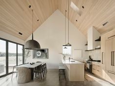 an open kitchen and dining area with wood ceilinging, large windows, and modern lighting fixtures