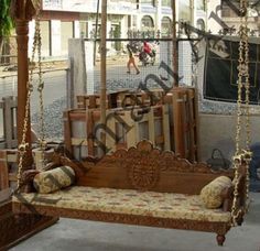 an old fashioned wooden swing bed in the middle of a room with lots of furniture