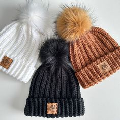 three beanies with pom - poms on them sitting next to each other