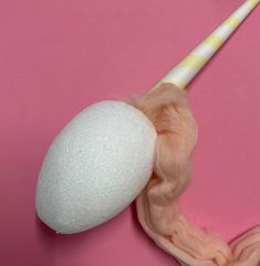 a wool ball and cotton swab on a pink surface with a toothbrush sticking out of it