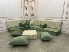 a large green couch sitting in the middle of a room with lots of pillows on it