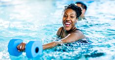 two people are in the water with blue dumbs and one is smiling at the camera