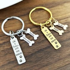 two key chains that say life is better with your dog and paw prints on them