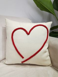 a white pillow with a red heart drawn on the front and back of it sitting on a couch