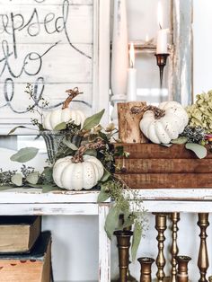 some white pumpkins and greenery on a table