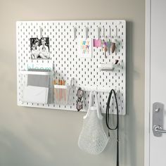 a white pegboard mounted to the side of a wall next to a purse and other items