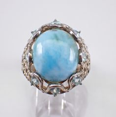 Vintage Sterling Silver Larimar and Blue Topaz ring. This ring is set with an Oval Larimar Cabochon Gemstone in the center and eight Pear shaped Blue Topaz around.  The center gem measures 16 X 13 mm and the Blue Topaz measure 4 X 3 mm each. This ring is finger size 9 and weighs 8.8 grams.  This ring measures 23 mm along the finger and sits 11 mm off the finger (height). This ring will be shipped promptly in a gift pouch. Oval Aquamarine Multi-stone Rings, Oval Multi-stone Aquamarine Ring, Blue Topaz Rings With Stones, Unique Larimar Jewelry For Anniversary, Collectible Oval Rings With Gemstone Accents, Oval Multi-stone Blue Topaz Gemstones, Oval Blue Topaz Multi-stone Gemstones, Oval Multi-stone Gemstones For Collectors, Oval Larimar Jewelry For Anniversary