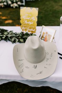 a white cowboy hat sitting on top of a table next to flowers and cards with writing all over it