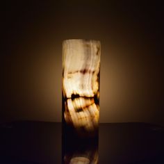 a marble vase sitting on top of a table next to a light that is turned on