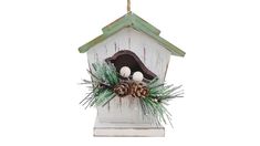 a birdhouse with pine cones and balls hanging from it's side on a white background