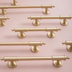 six brass door handles and knobs on a pink background