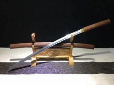 two wooden swords are on display in front of a black background and white tablecloth