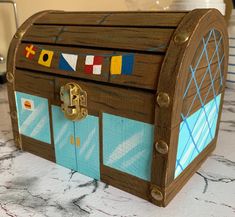 a wooden box with many different colored flags on the front and sides, sitting on a table