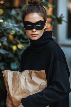 a woman wearing a black mask and holding a brown bag