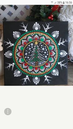 a christmas tree painted on a black canvas next to a teddy bear and other decorations