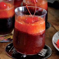 two glasses filled with liquid sitting on top of a table next to plates and cups