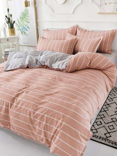 a bed with pink and grey striped comforters