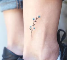 a small tattoo on the ankle of a woman's foot, with blue flowers