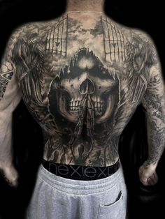 a man's back is covered in tattoos and has two skulls on his chest