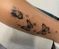 a woman's arm with three butterflies on it and stars in the sky above