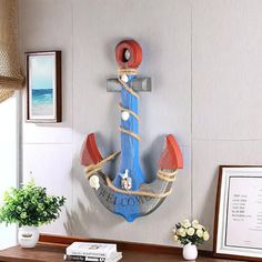 an anchor is mounted on the wall next to a potted plant and framed pictures