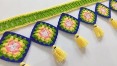 crocheted tassels are lined up on a white surface with green and yellow trim