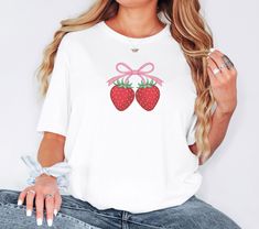 Sweeten your style with our Strawberry T-Shirt! Featuring cute strawberries and a bow, this comfy and stylish tee is perfect for casual wear and strawberry lovers. Ideal as a gift or summer wardrobe addition. Order your custom design today! Please note that the adult t-shirts are Gildan branded. Fabric: Modern, fits perfectly. 100% Soft ring-spun cotton. 90% cotton 10%polyester for Athletic Heather Size:  Please refer to Size Chart in the images for measurement of any garment Design Colour: We try our best to match colours accurately to what is seen on the screen. Colours may vary slightly in reality to what is seen on your screen due to projected light (computer light) and reflected light (when t-shirt is in hand)   Care : Warm wash, inside out. Do not tumble dry. Do not bleach. Do not dr Cute Strawberry Print T-shirt As Gift, Cute Fruit Print T-shirt, Sweet Summer T-shirt As Gift, Sweet T-shirt For Summer Gift, Sweet Summer Tops As Gift, Sweet Summer Tops For Gift, Strawberry T Shirt, Modern Fits, Fruits Decoration