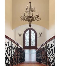 a chandelier hanging from the ceiling in front of a doorway and stairs leading to another room