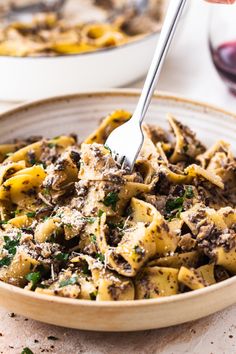 a bowl full of pasta with mushrooms and parmesan cheese on top, being lifted by a fork