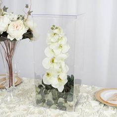 a vase filled with white flowers sitting on top of a table next to a plate