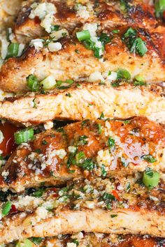 meat covered in sauce and green onions on top of rice with tomatoes, asparagus and parmesan