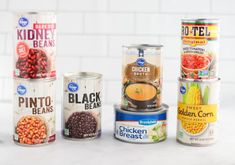 four cans of canned food sitting on top of a white counter next to each other