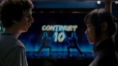 two people standing in front of a television screen with the words continuer 10 on it