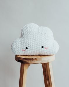 a white cloud pillow sitting on top of a wooden stool