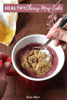 a person holding a spoon over a bowl of food on top of a wooden table