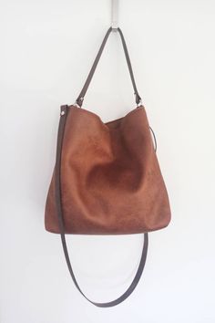 Medium/ large hobo style bag The body of the bag is made of high quality faux vegan leather in rustic distressed cognac brown color. (Also available in black- if you want the black version please leave a note on checkout) It is fully lined with cotton fabric in light brown color. * two inner slip pockets perfect for phone, keys, cardholder etc. *closes with magnetic snap button *the shoulder strap and the crossbody strap (if added) are made of thick cowhide leather for extra support * additional Soft Leather Hobo Bag For Errands, Everyday Faux Leather Hobo Shoulder Bag, Hobo Bag With Adjustable Strap For Errands, Everyday Soft Faux Leather Hobo Bag, Faux Leather Hobo Bag With Removable Pouch For Everyday, Brown Leather Hobo Bag For Everyday Use, Hobo Shoulder Bag With Detachable Strap For Errands, Hobo Bucket Bag With Adjustable Strap For Errands, Versatile Brown Shoulder Bag For Errands