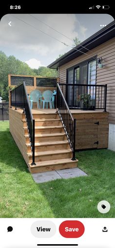 a wooden deck with black railing and chairs on the grass next to a house in the background